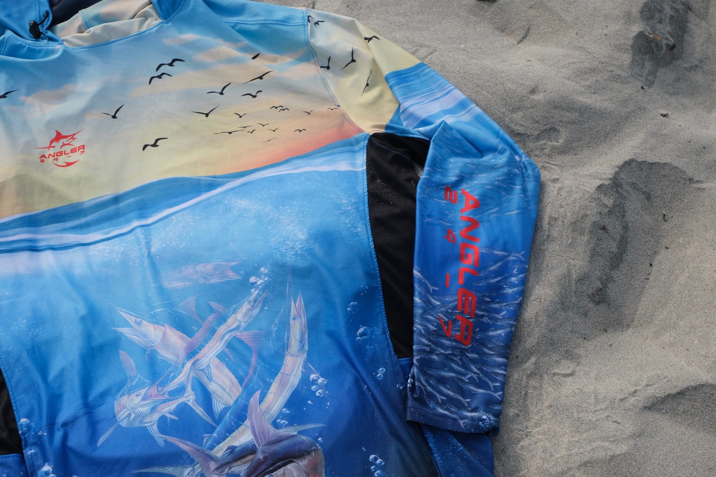 Angler 24-7 fishing shirt with logo on sand.