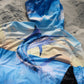 Angler 24-7 hoodie with marlin fish design on sandy beach.