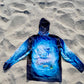 Angler 24-7 fishing shirt with fish design on sand.
